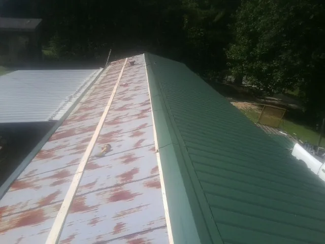 Old rusted panels beside newly installed green metal roofing — Wind Damage Roof Repair by Roofing Brothers in Interlachen