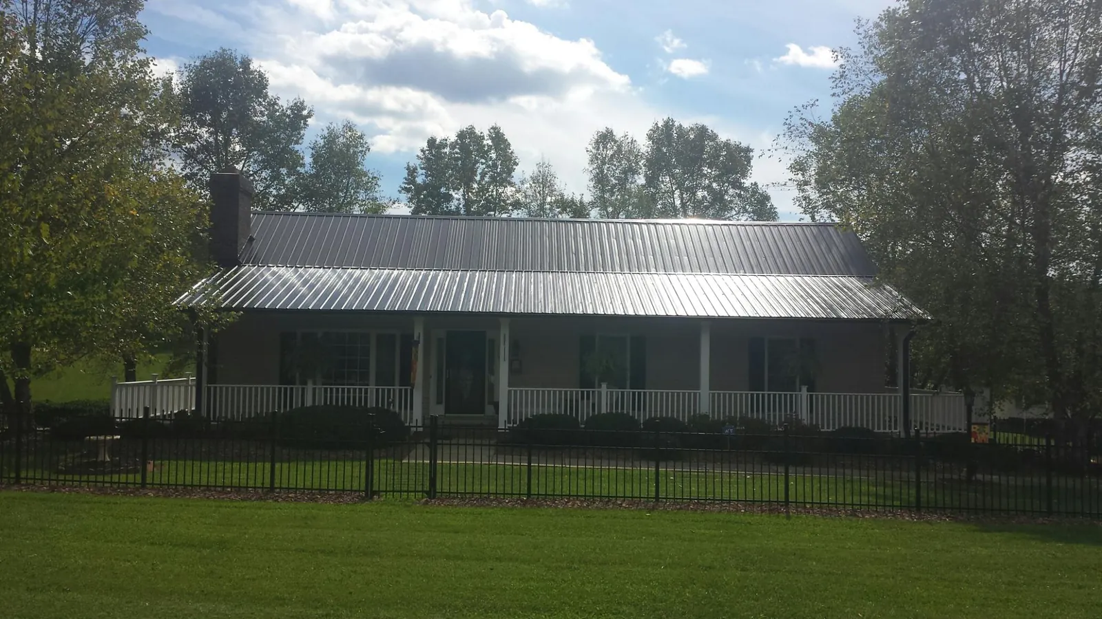Gray metal roof on a brick ranch with a full width front porch — Gutter Guard Installation work by our crew in Interlachen